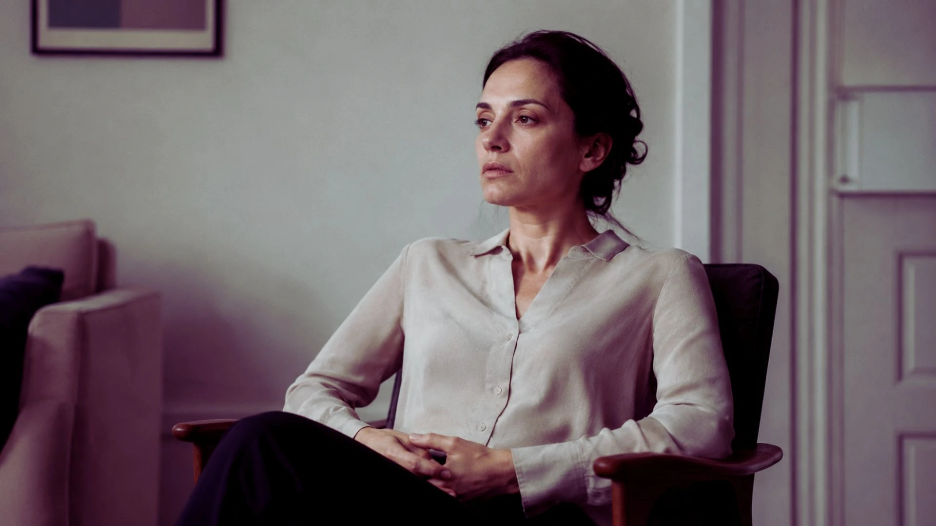Persona seduta con postura rigida e sguardo assorto, simbolo di tensione fisica trattenuta e corpo in difesa silenziosa.